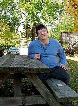 Harry, a consumer with SERV Centers Passaic County for 20 years, sits in the back yard of his apartment building on a recent day in autumn.